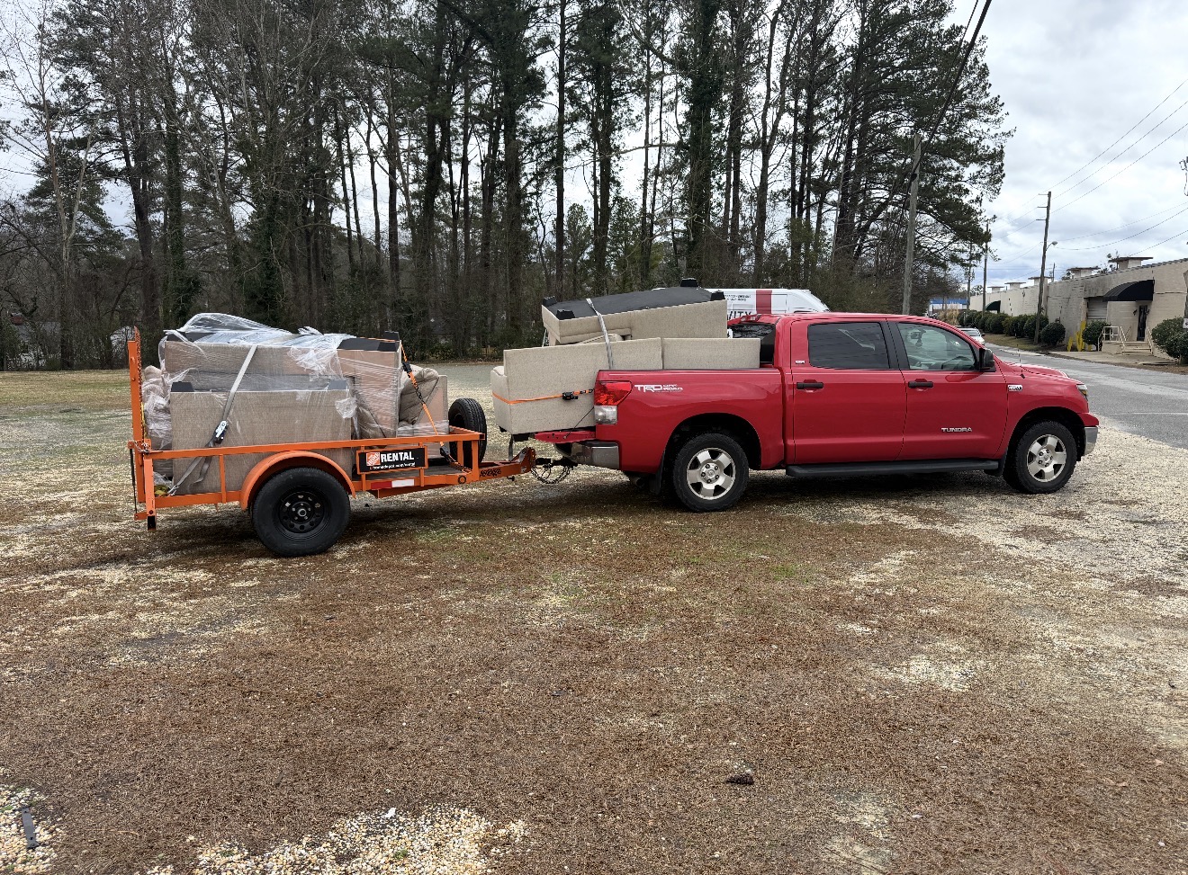 Red pickup truck and rented trailer loaded with sofa sections